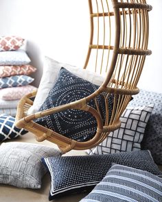 a wicker chair hanging from the ceiling in front of pillows and cushions on display