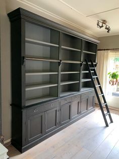 a ladder leaning up against a bookcase in a room with hardwood floors and white walls