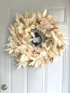 a wreath is hanging on the front door, with flowers and leaves around it's edges