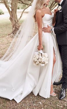 a bride and groom posing for a photo in front of trees with their wedding bouquet