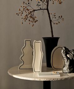 a table topped with vases filled with flowers next to a small black and white plant