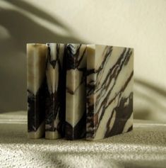 three pieces of soap sitting on top of a white table cloth covered in black and white marble