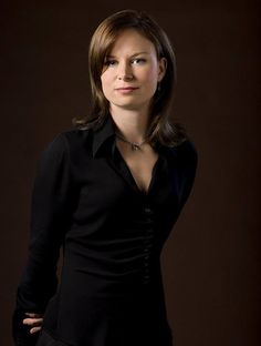 a woman is posing for a portrait in black shirt and jeans with her hands on her hips