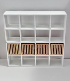 a white bookcase with wooden shutters on the front and bottom shelves in different sizes