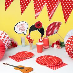 a table topped with red and white polka dot paper plates next to cupcakes