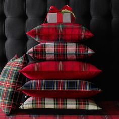 pillows stacked on top of each other in front of a black headboard with red and green plaid