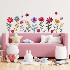 a living room with flowers painted on the wall and stuffed animals sitting on the floor