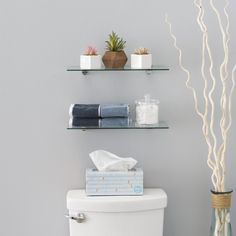 a toilet with two shelves above it and some towels on the tank next to it