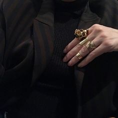 a close up of a person wearing gold rings