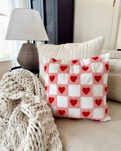 a white and red pillow sitting on top of a couch next to a lamp in a living room