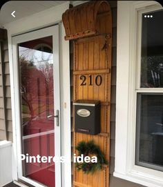 a mailbox on the side of a house next to a door with wreaths