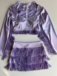 The space cowgirl skirt set includes a long sleeve cropped blouse and mini skirt. The crop top features breast cups and a back zipper. This design is made to order and can be customized by color and size. The pictured look is a lavender satin stretch with purple glitter fringe trim. Both the fringe and fabric can be customized. Measurements needed: Bust Waist Armpit to Wrist Hi Waist Hips Belly Button to desired skirt hem Space Cowgirl Theme Outfit, Purple Space Cowgirl, Purple Glitter Outfit, Osheaga Outfits, Sparkly Cowgirl Outfit, Space Cowgirl Outfits, Space Cowgirl Theme, Cowgirl Costume Diy, Purple Cowgirl