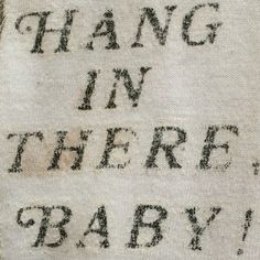 the words hang in there baby written on a piece of cloth with black ink and some type of writing