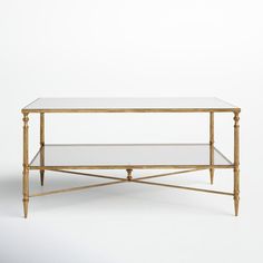 a golden coffee table with glass shelves on each side and gold trim around the edges