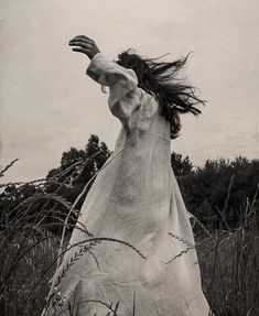 a woman in a long dress is flying through the air with her hair blowing back