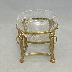 a glass bowl sitting on top of a stand with gold trimmings and handles