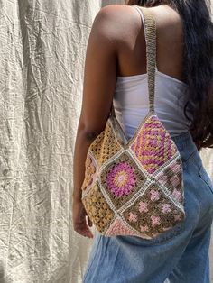 a woman carrying a crocheted purse in front of a white curtain with her back to the camera