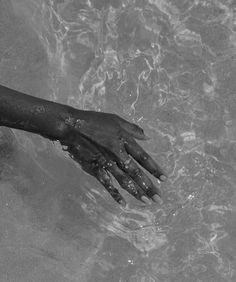 a person's hand reaching for something in the water