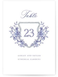 a wedding table number card with blue flowers and leaves on the front, in an ornate frame