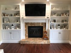 a living room with white built in cabinets and a fireplace