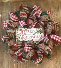 a christmas wreath with the words merry christmas on it and plaid bows hanging from the front door