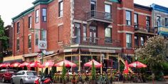 an old brick building with many red umbrellas on the street in front of it