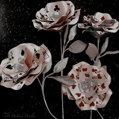 three flowers with playing cards on them in the dark night sky and snow flecks