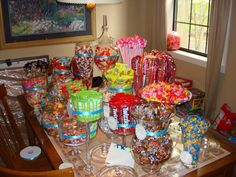 a table filled with lots of candy and candies next to a lamp on top of a wooden table