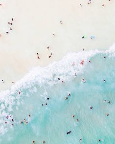 an aerial view of people swimming in the water and on the beach, from above