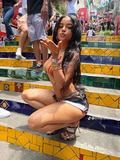 a woman sitting on some steps with her hand up to her mouth and hands in front of her face