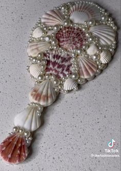 a brooch with seashells and pearls on it's side, sitting on a table