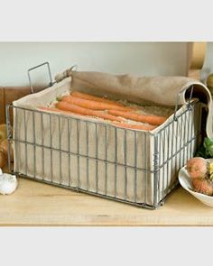 carrots and onions are sitting in a basket on the table next to other vegetables