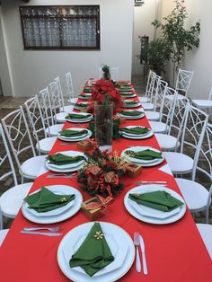 the table is set for christmas dinner with red and green napkins, silverware, and poinsettis