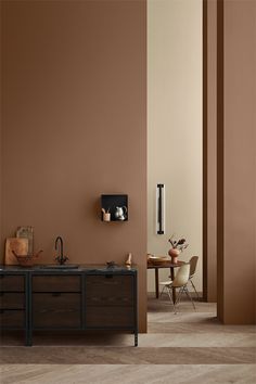 a kitchen with brown walls and wooden cabinets in the center, along with a dining room table