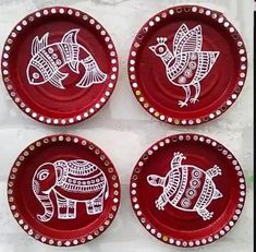 three red plates with white designs on them and one has an elephant in the middle