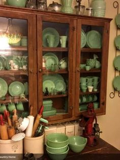 an old china cabinet with green dishes on it