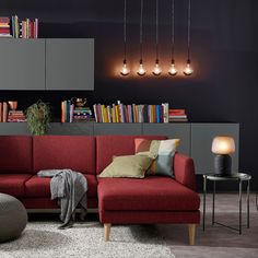 a living room with a red couch and bookshelf on the wall next to it