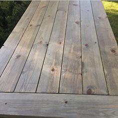 a close up of a wooden deck with grass in the background