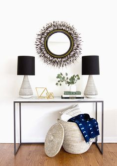 a white table topped with two lamps next to a mirror and lamp shade on top of it