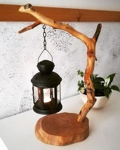 a wooden table topped with a lamp next to a tree branch and potted plant