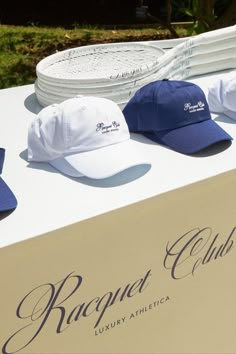 several hats are on display for sale at an outdoor event in front of a sign that reads, respect club luxury athletic