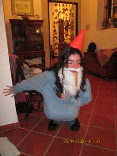 a woman wearing a gnome hat and holding a pencil in her mouth while sitting on the floor