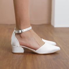 a woman's feet in white shoes on a wooden floor with her legs crossed