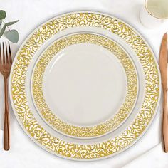 a white plate with gold designs on it next to silverware and utensils