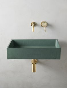 a green sink and faucet in a white bathroom with gold fixtures on the wall