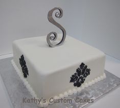 a square cake with white frosting and black decorations