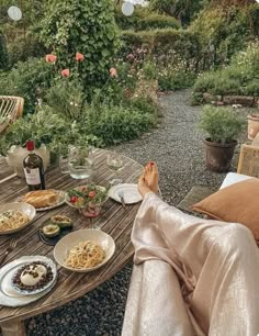 a table with food and wine on it in front of an outdoor patio area that has flowers