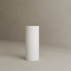 a white vase sitting on top of a table next to a black object in the background