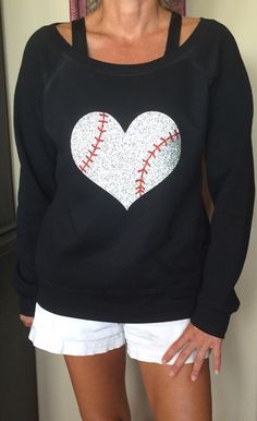 a woman wearing a black sweatshirt with a heart shaped baseball on it's chest