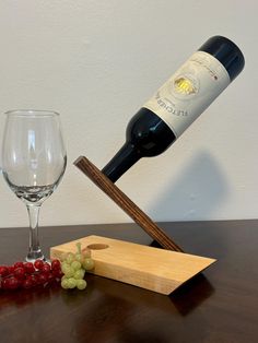 a bottle of wine is being poured into a glass next to grapes and a cutting board